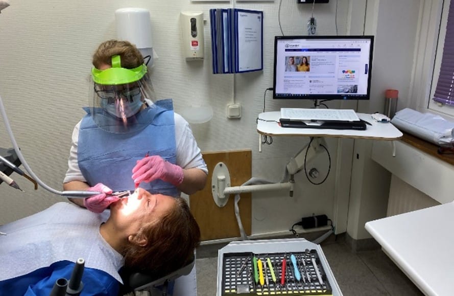 Tandläkare behandlar patient med god ergonomi och korrekt uppställning av utrustning i behandlingsrum.